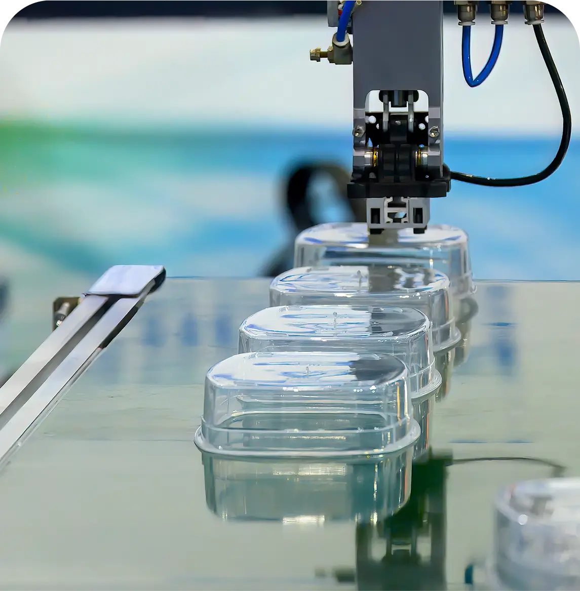 Robotic arm placing plastic containers on conveyor.