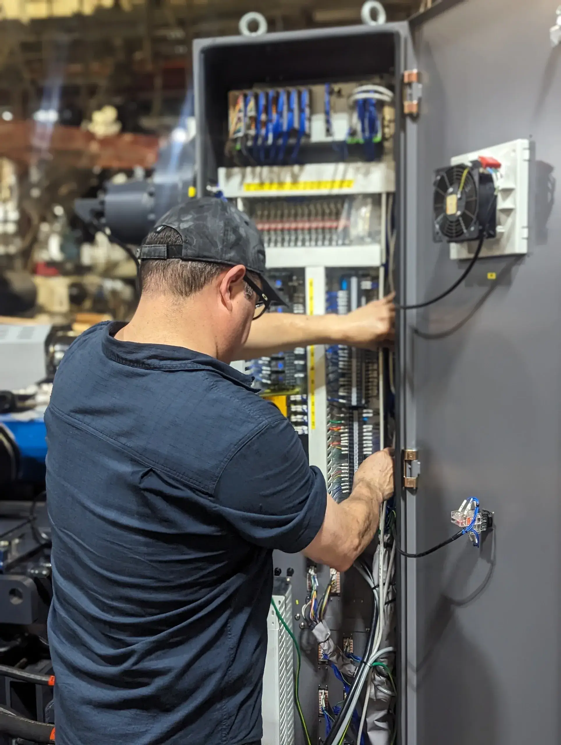 Technician working on electrical control panel.