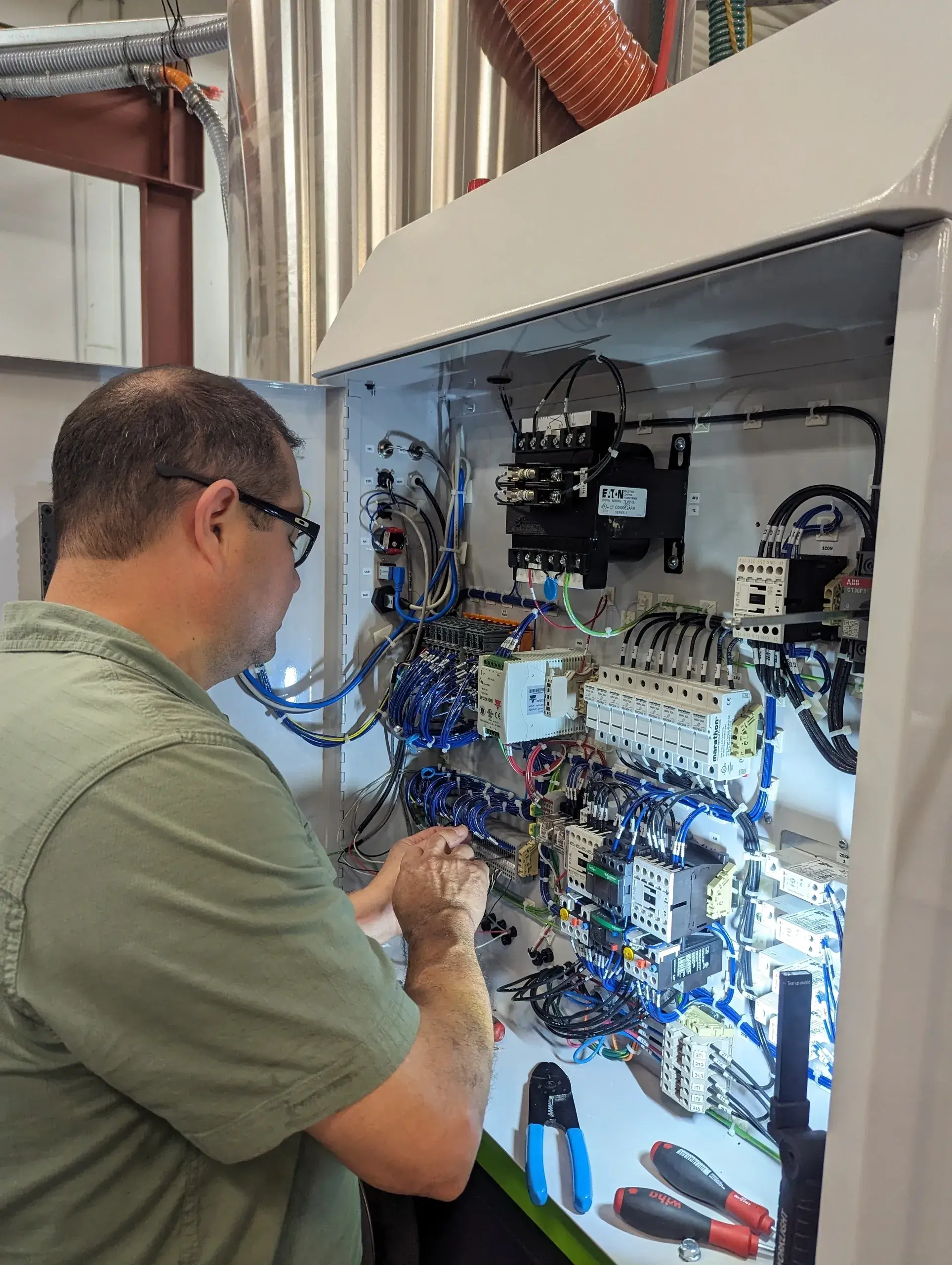 Technician working on electrical control panel.
