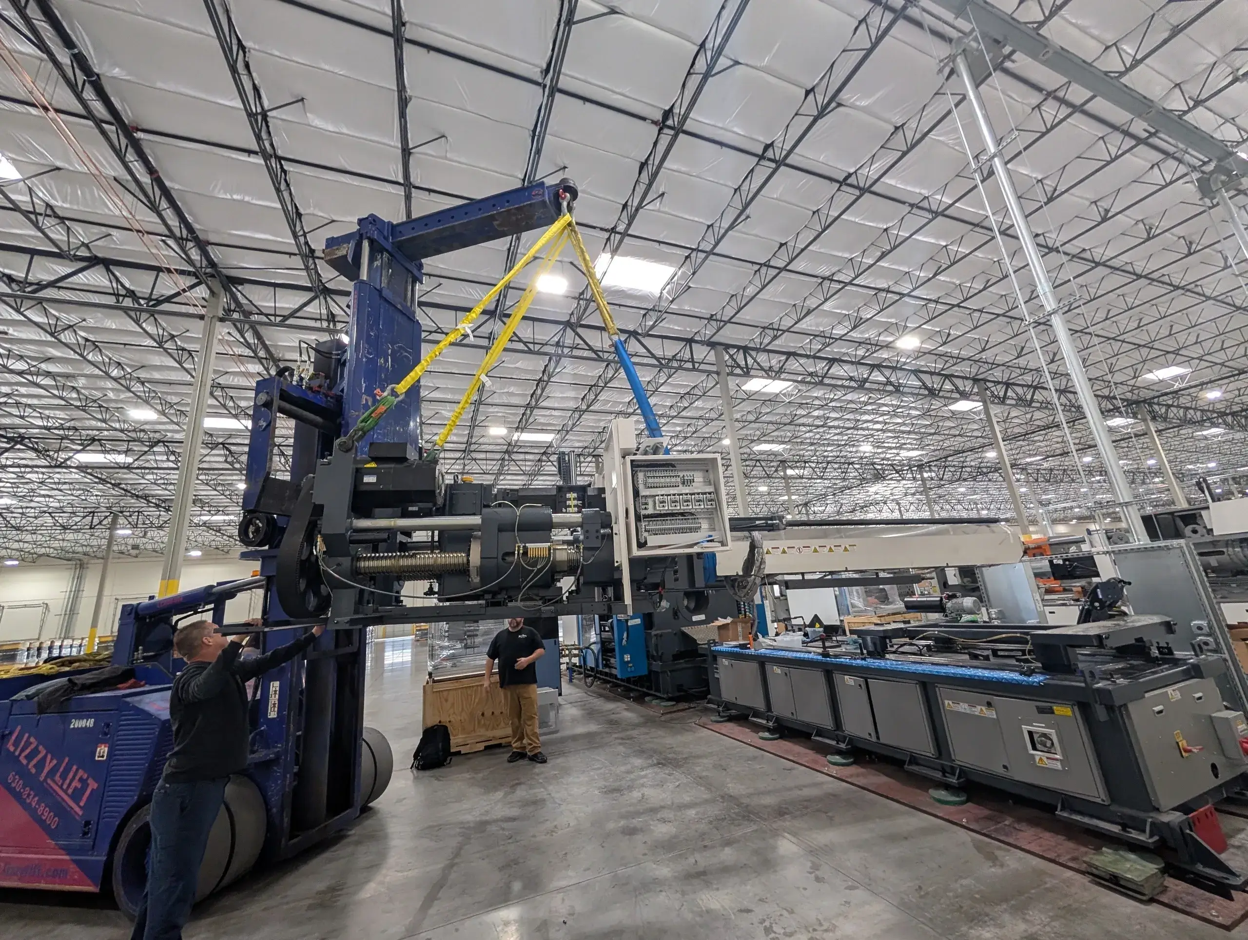 Machine being lifted in a large warehouse.